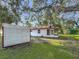 Backyard view of house exterior, a shed and mature shade trees on a large lawn at 1444 Oak Haven Dr, Safety Harbor, FL 34695