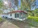 The exterior of a cozy home includes a screened porch, green lawn and mature shade trees at 1444 Oak Haven Dr, Safety Harbor, FL 34695