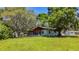 Exterior view of a charming home surrounded by a lush green lawn and mature trees at 1444 Oak Haven Dr, Safety Harbor, FL 34695