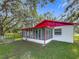 A screened porch on the home's exterior is surrounded by a beautiful green lawn and mature trees at 1444 Oak Haven Dr, Safety Harbor, FL 34695