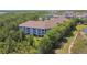 Drone view of condo building surrounded by lush green trees and a serene pond on a sunny day at 1610 Raena Dr # 204, Odessa, FL 33556
