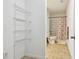 Bright bathroom featuring open shelving and shower-tub combination with patterned curtain at 1610 Raena Dr # 204, Odessa, FL 33556