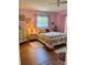 Charming bedroom with pink walls, floral bedding, and natural light from the window at 3516 Lake Bayshore Dr # K109, Bradenton, FL 34205