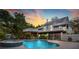 Resort-style home featuring an elevated deck, modern pool, and a fenced yard against a sunset backdrop at 380 Wellington Ave, Oldsmar, FL 34677