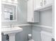 Well-lit half bathroom featuring a pedestal sink, wall cabinet, and elegant fixtures at 380 Wellington Ave, Oldsmar, FL 34677