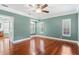 An empty bedroom with a ceiling fan, hardwood floors, teal walls, and white shutters at 380 Wellington Ave, Oldsmar, FL 34677