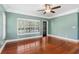 A room with teal walls, wooden floors, white shutters, and a ceiling fan at 380 Wellington Ave, Oldsmar, FL 34677