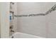White tiled shower/tub with a niche for toiletries and a decorative mosaic stripe at 4257 Rosatti Rd, Wesley Chapel, FL 33543