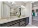Bathroom featuring dual sinks, granite countertop, modern lighting fixtures, and an open doorway to the walk-in closet at 4257 Rosatti Rd, Wesley Chapel, FL 33543
