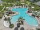 Aerial view of a resort-style pool surrounded by palm trees, cabanas, and lounge chairs at 4257 Rosatti Rd, Wesley Chapel, FL 33543