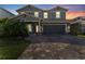 Stunning two-story home featuring elegant exterior lighting, a paved driveway, and lush tropical landscaping at 4583 Emprise Way, Land O Lakes, FL 34638