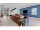 Spacious living room with a comfortable leather couch, blue accent wall, and modern decor at 4583 Emprise Way, Land O Lakes, FL 34638