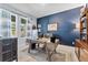Office space featuring a wooden desk, navy accent wall, and natural light from the window at 4583 Emprise Way, Land O Lakes, FL 34638