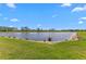 Picturesque pond with a grassy shoreline and clear skies, enhancing the natural beauty of the area at 4583 Emprise Way, Land O Lakes, FL 34638