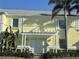 Charming yellow condo exterior with white trim, lush landscaping, and shared pergola entrance at 5242 Beach Se Dr, St Petersburg, FL 33705