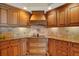 Close up of kitchen with wooden cabinetry, granite countertops and backsplash, and a modern stovetop range at 5301 Gulf Blvd # B508, St Pete Beach, FL 33706