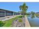 Landscaped backyard featuring a tranquil pond view, mature palm trees, and a screened-in lanai at 5785 Bay Pines Lakes Blvd, St Petersburg, FL 33708