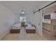 Bedroom with twin beds and barn door to bathroom, all with neutral tones and tile floors at 5785 Bay Pines Lakes Blvd, St Petersburg, FL 33708