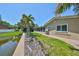 Beautiful home exterior showcasing a serene backyard pond view, palm trees, and a screened-in patio at 5785 Bay Pines Lakes Blvd, St Petersburg, FL 33708