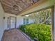 Inviting front porch area with brick flooring and tropical landscaping with lush ferns and greenery at 5785 Bay Pines Lakes Blvd, St Petersburg, FL 33708
