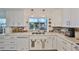 Charming kitchen includes white cabinets, modern appliances, and a view of the screened-in porch overlooking the lake at 5785 Bay Pines Lakes Blvd, St Petersburg, FL 33708