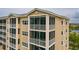 Exterior view of a modern beige condominium featuring screened-in balconies and well-maintained landscaping at 7040 Key Haven Rd # 601, Seminole, FL 33777
