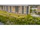 Aerial view of a multi-story condo building showing exterior design, lush landscaping, and covered parking spaces at 7040 Key Haven Rd # 601, Seminole, FL 33777