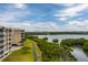 Exterior view of a tan condo building showcasing surrounding landscape, a sidewalk, and peaceful waterways at 7040 Key Haven Rd # 601, Seminole, FL 33777