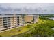 A scenic aerial view showcasing the exterior of a tan condo building near green foliage, a sidewalk, and waterways at 7040 Key Haven Rd # 601, Seminole, FL 33777