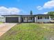 Inviting single-story home with a dark garage door, contrasting trim, and manicured lawn at 7327 Jasmine Blvd, Port Richey, FL 34668