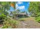 The landscaped backyard boasts a screened porch, verdant lawn, and beautiful tropical trees and plants at 7414 Mint Julep Dr, Riverview, FL 33578