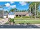 Charming single Gathering home featuring a beautifully landscaped front yard, lush green lawn, and mature palm trees at 7414 Mint Julep Dr, Riverview, FL 33578