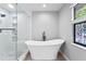Modern bathroom featuring a freestanding tub, glass-enclosed shower and decorative stained-glass window at 7902 River Ridge Dr, Temple Terrace, FL 33637