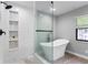 Modern bathroom with a glass-enclosed shower featuring built-in shelves and a freestanding soaking tub at 7902 River Ridge Dr, Temple Terrace, FL 33637