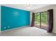 Bright bedroom with a blue accent wall, carpet, and sliding glass doors leading to an outdoor space at 7902 River Ridge Dr, Temple Terrace, FL 33637