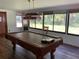Game room with a pool table with a lamp hanging above it, dark wood floors, and lots of windows at 819 Satinleaf Ave, Oldsmar, FL 34677