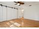 Bedroom with light wood floors, sliding barn doors, and a peek into the bathroom at 8350 Monarch Cir, Seminole, FL 33772