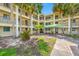 Exterior of a condo building with palm trees, green lawn, and a covered walkway at 865 S Gulfview Blvd # 306, Clearwater Beach, FL 33767