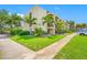 Three-story condominium building featuring lush landscaping, a sidewalk, and well-maintained lawn at 865 S Gulfview Blvd # 306, Clearwater Beach, FL 33767