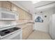 Kitchen with white appliances and light wood cabinets under a skylight at 865 S Gulfview Blvd # 306, Clearwater Beach, FL 33767