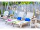 Comfortable outdoor lounge area features white Adirondack chairs, side tables, and views of the backyard at 1208 Bay Pine Blvd, Indian Rocks Beach, FL 33785