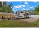 Exterior features of RV with awning, outdoor furniture, and barbecue grill on a grassy, gravel lot at 121 Pennsylvania Ave, Palm Harbor, FL 34683