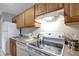Kitchen featuring wood cabinets, white appliances, tile floors, and breakfast bar at 1400 Gandy N Blvd # 1701, St Petersburg, FL 33702