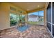Screened patio with brick flooring overlooks the backyard with seating arrangement at 14174 Thoroughbred Dr, Dade City, FL 33525