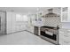 White kitchen features stainless steel appliances, custom cabinets and a decorative backsplash at 1493 Sea Gull S Dr, St Petersburg, FL 33707