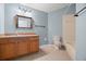 Bathroom with a wooden vanity, framed mirror, tiled floor, and a toilet beside the bathtub at 19232 Barred Owl Ct, Land O Lakes, FL 34638
