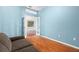 Bedroom featuring an open doorway and blue walls with a gray sofa and wood floors at 19232 Barred Owl Ct, Land O Lakes, FL 34638