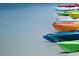 Colorful kayaks rest on the shore, their bright hues contrasting with the white sand and calm water at 2387 Hanover Dr # 2387, Dunedin, FL 34698
