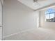 A bright bedroom with neutral carpet, light colored walls, ceiling fan, and large arched window at 2387 Hanover Dr # 2387, Dunedin, FL 34698