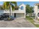 Inviting two-story home featuring an attached garage, manicured lawn, and a mature palm tree in the front yard at 2387 Hanover Dr # 2387, Dunedin, FL 34698